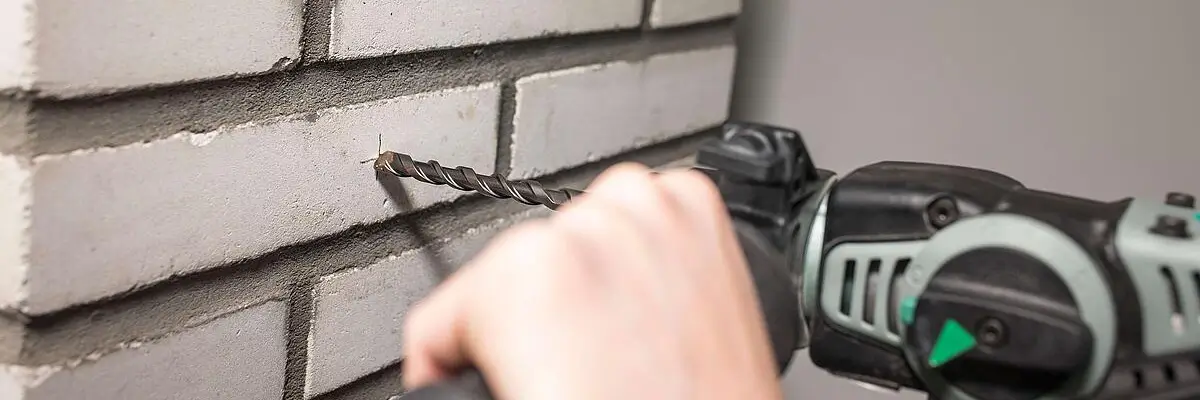Eine Person bohrt mir einem Steinbohrer durch eine Wand