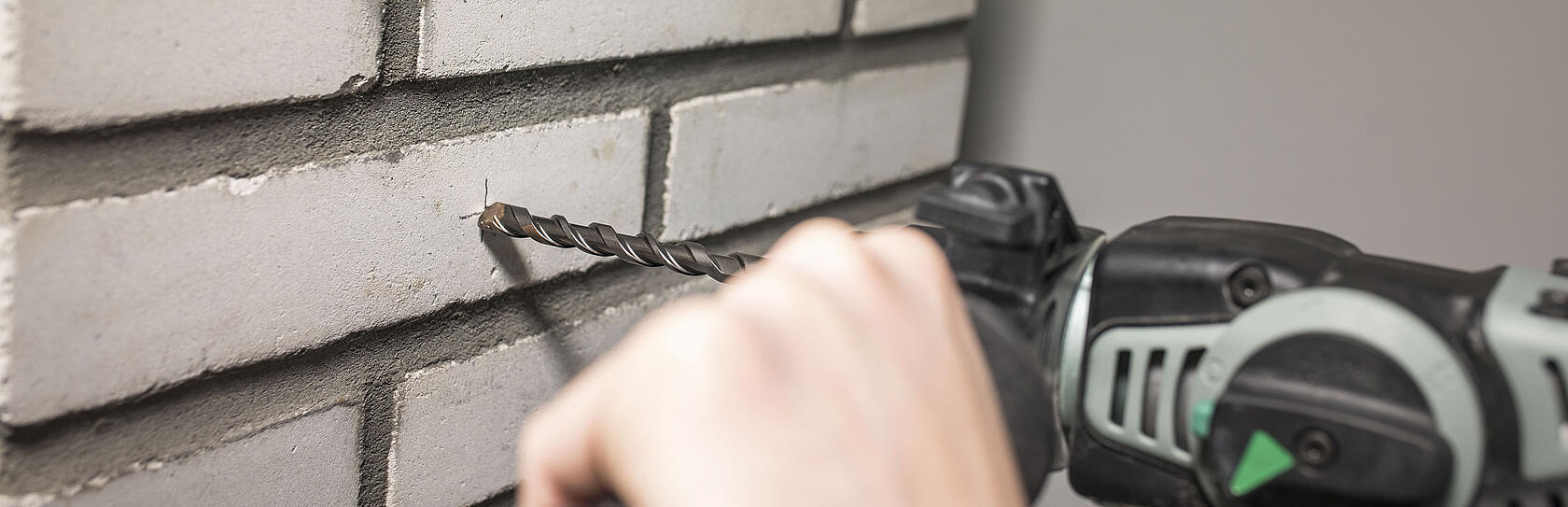 Bohrmaschine bohrt in weißen Stein