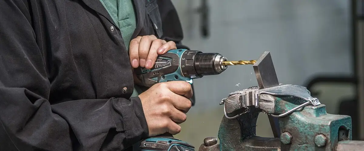 Eine Person nutz einen Metallbohrer um durch Metall zu bohren